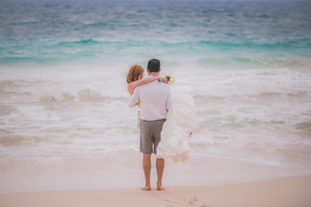 A groom holds his bride at Lanikai Beach during their elopement.