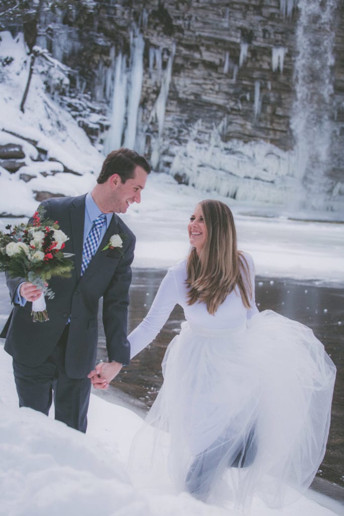 A couple walks through snow during their winter elopement.