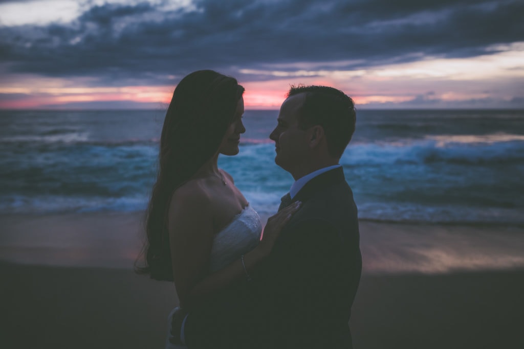 A bride and groom enjoy their first sunset as a married couple in Oahu.