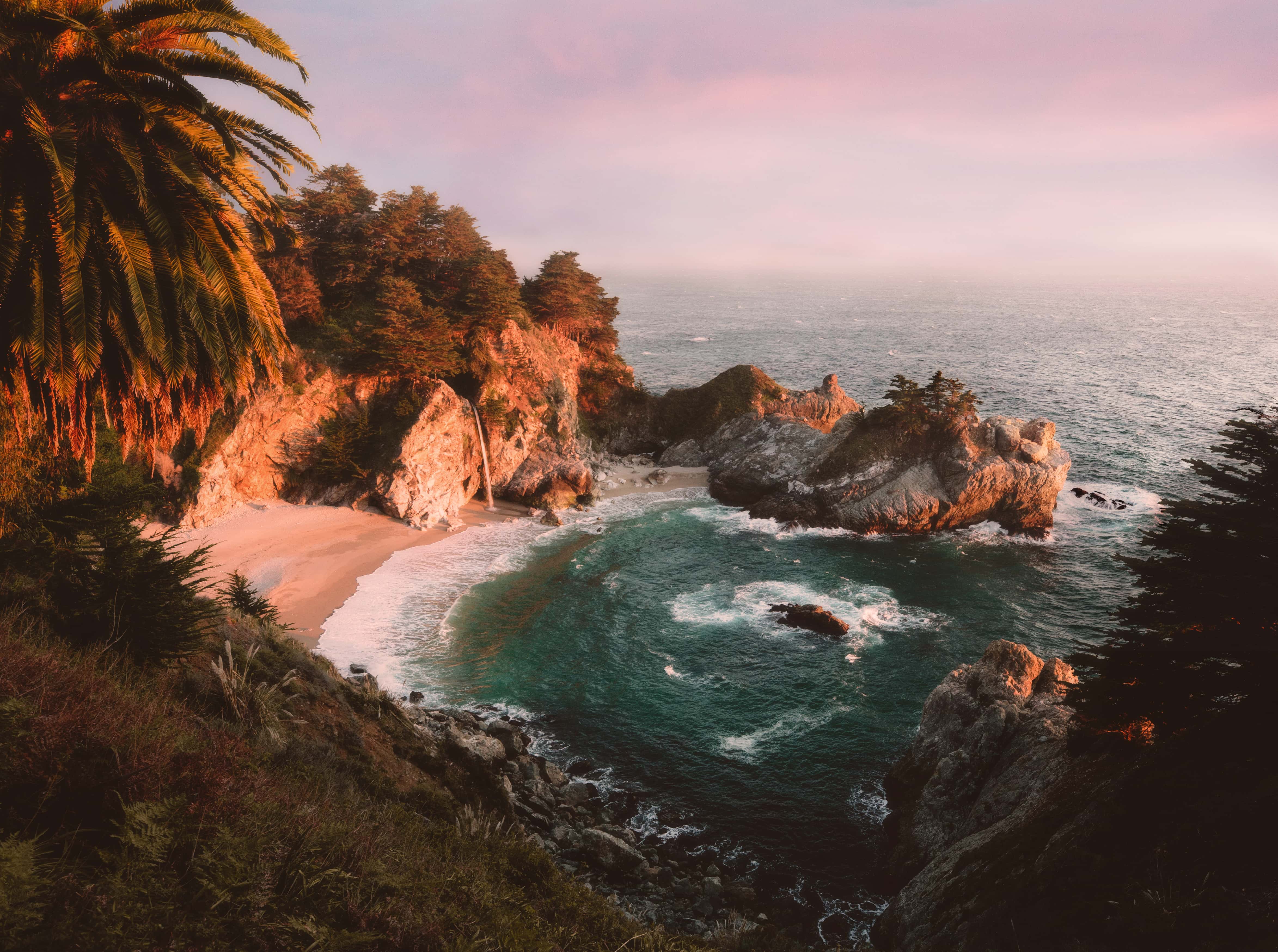 A colorful sunset mixed with golden sunset light on the hillsides at McWay Falls in Julia Pfeiffer Burns State Park.