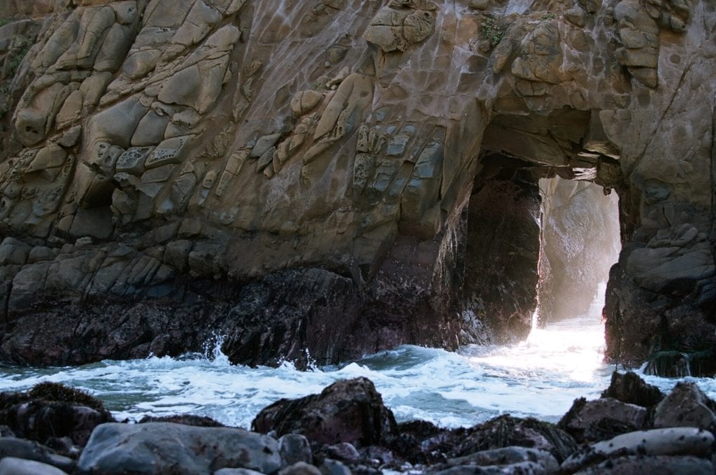 Sunlight pouring through the keyhole of the keyhole arch at Pfeiffer Beach.
