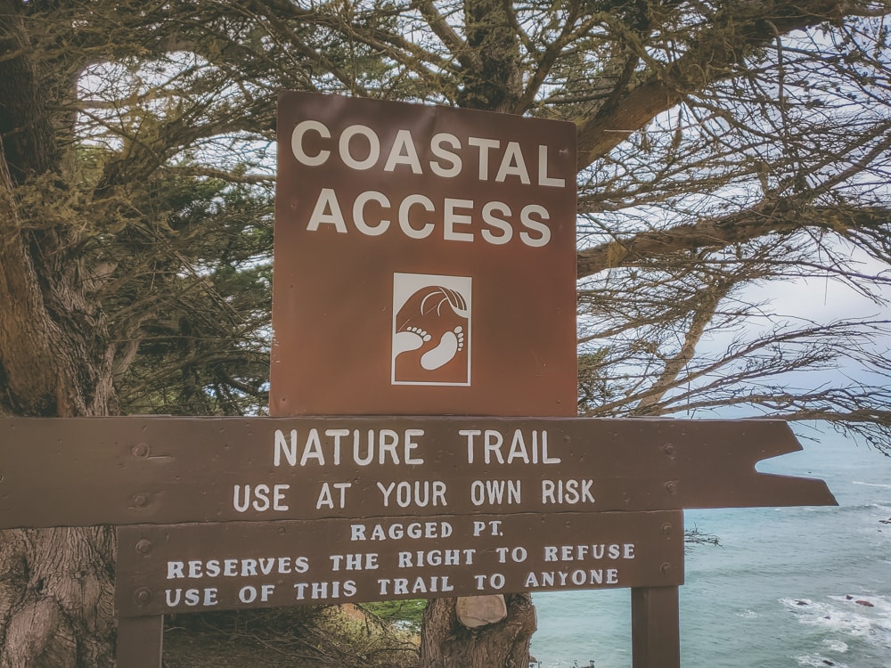 A sign denoting a nature trail and coastal access at the Ragged Point Inn
