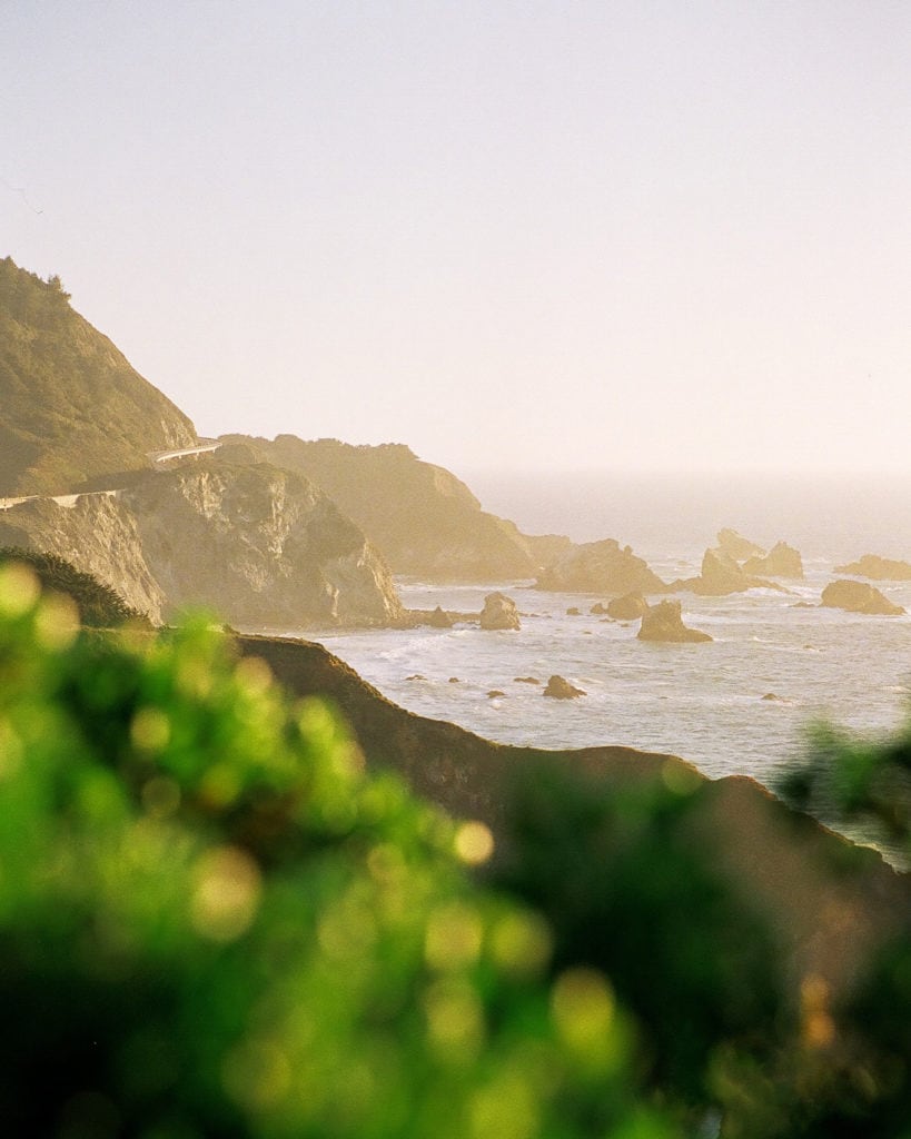 A view of Highway 1 and the rocky coast at sunset in Big Sur